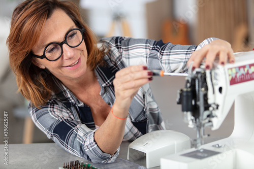mature woman repairing a sewing machine