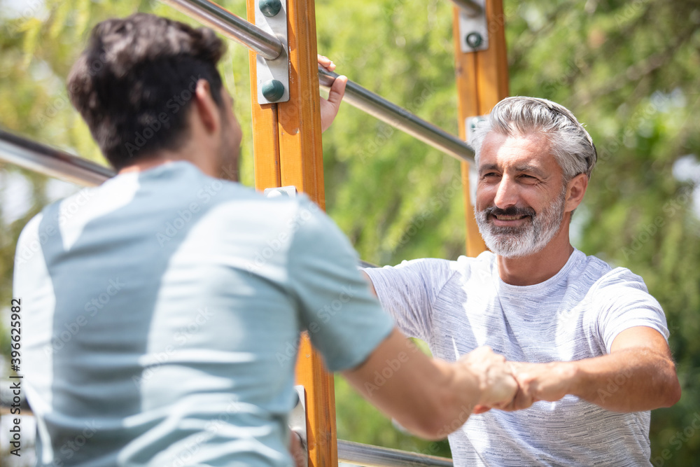 male mature friends exercising at the park