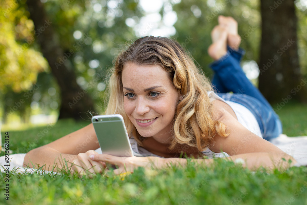 young girl laying the park using mobile phone young girl laying the park using mobile phone