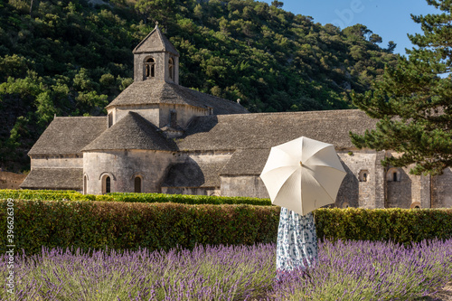 Girl with a white umbrella in a lavander field in front of an old abbey