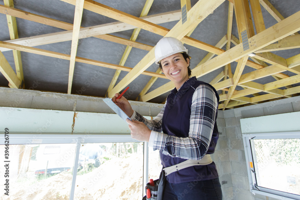 female builder using screwdriver on wooden beam