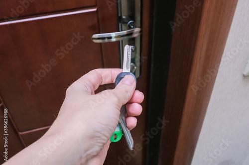 A hand holding a key and inserting it in a keyhole in order to open or lock a door, home security and protection concept