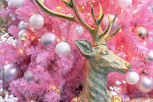 Gold deer on the background of a pink Christmas tree with white and silver balls.