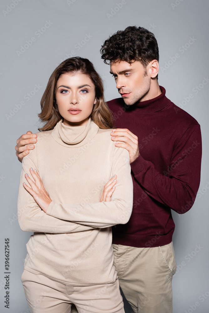 young couple in jumpers posing isolated on grey young couple in jumpers posing isolated on grey