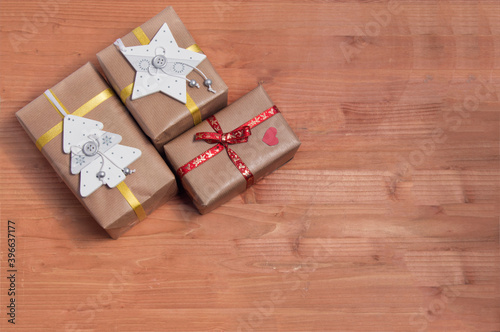 wooden background with three christmas gift packages viewed from above