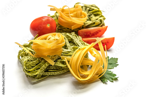 dry fettuccine pasta and tomatoes on white surface