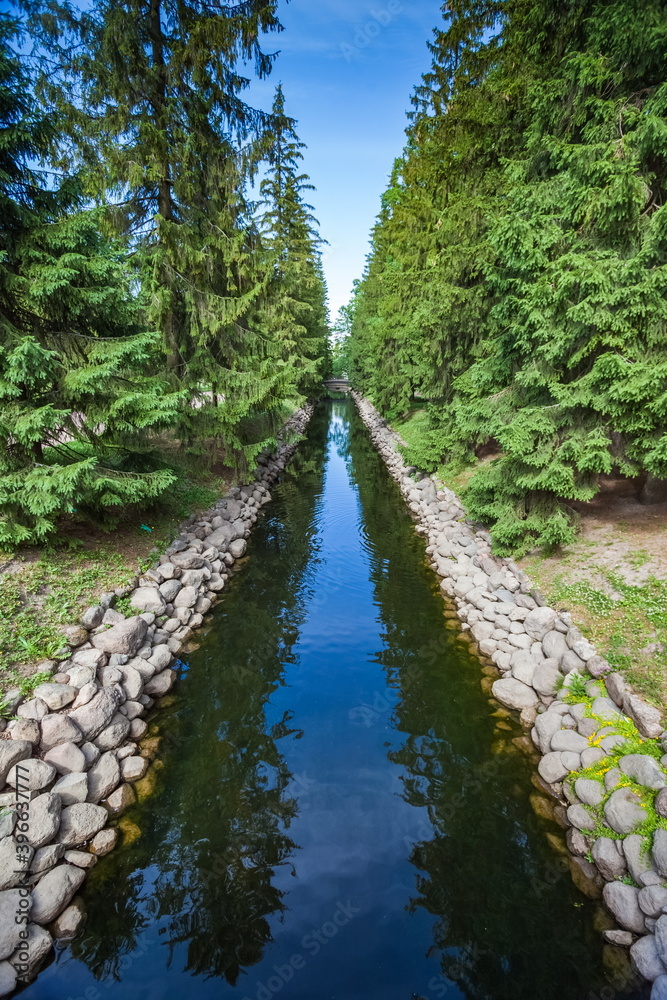 Obraz premium Summer landscape in a city Park with trees, grass, river, sky with clouds