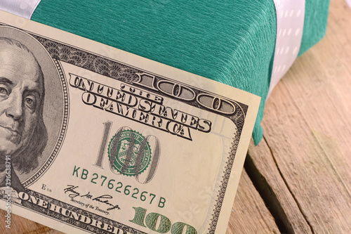 Dollars money along with a gift, a symbol of the crisis, venality, hoarding and wealth. American money on wooden background.