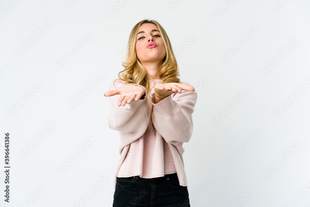 Young caucasian blonde woman folding lips and holding palms to send air kiss.