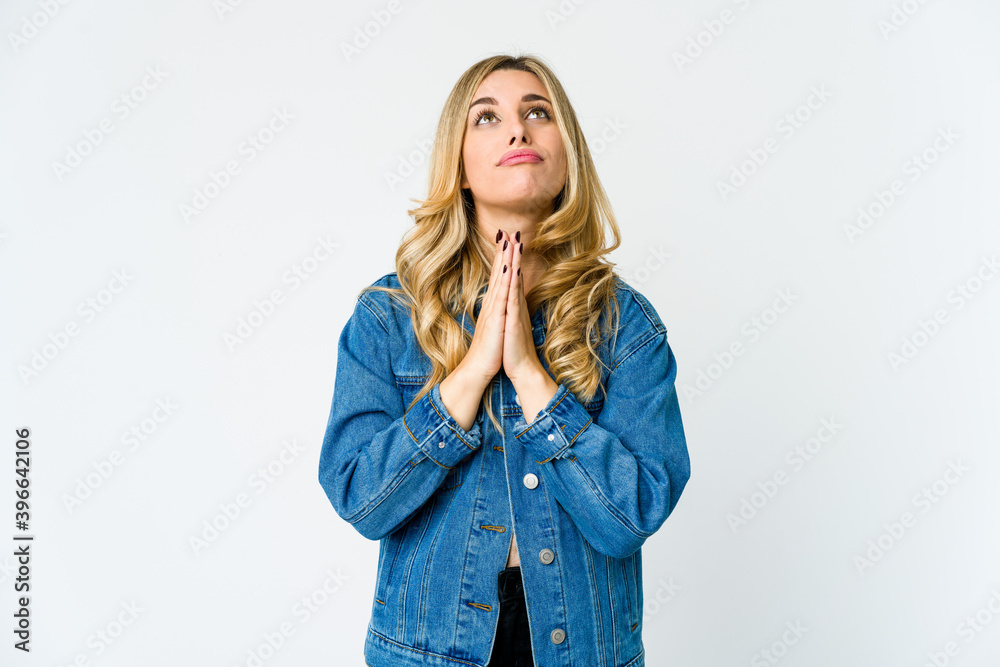 Young caucasian blonde woman holding hands in pray near mouth, feels confident. Young caucasian blonde woman holding hands in pray near mouth, feels confident.