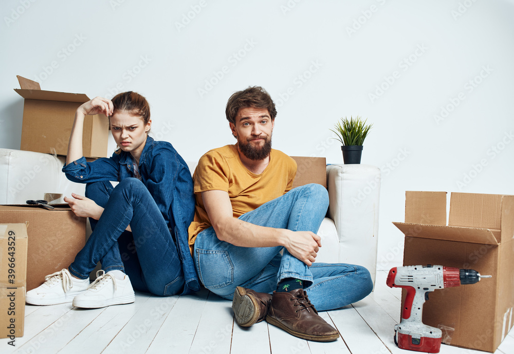 A man and a woman are sitting on the floor with open boxes and tools for repair A man and a woman are sitting on the floor with open boxes and tools for repair