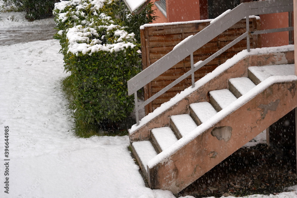 Outdoor stairs of a residential building covered with a layer of fresh  snow. The slippery surface is a danger and accident risk.