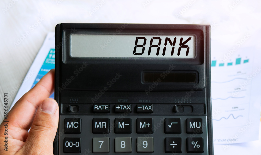 The word MARKETING is written on the calculator. Business man holding a calculator in his hand. Top view of the desktop and business charts. Finance or business concept. The word MARKETING is written on the calculator. Business man holding a calculator in his hand. Top view of the desktop and business charts. Finance or business concept.