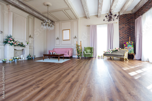 Bright cozy living room design. Wooden floor, fresh flowers and white columns on the walls