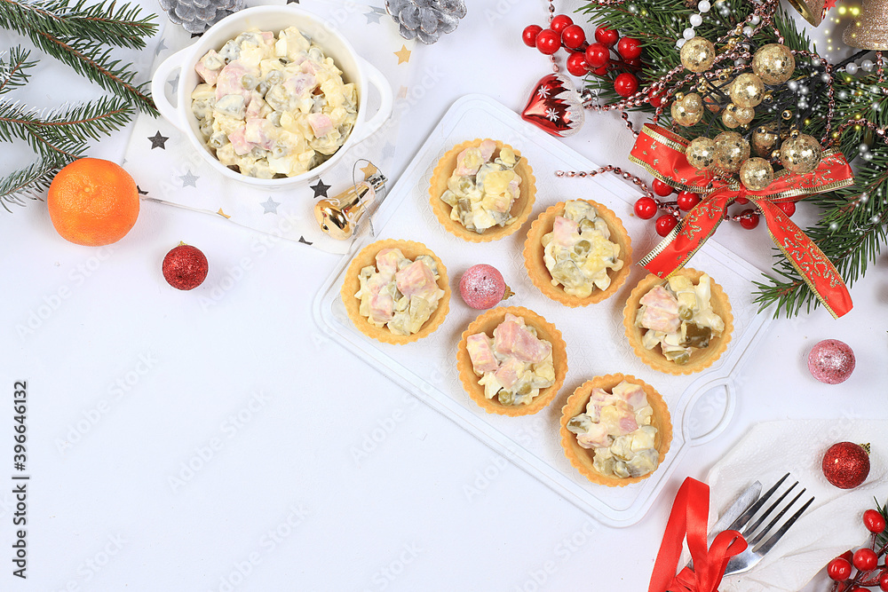 Christmas new year dishes, traditional festive olivier salad with fir branches and cones and decorations on a light table, dish design idea, selective focus, place for text