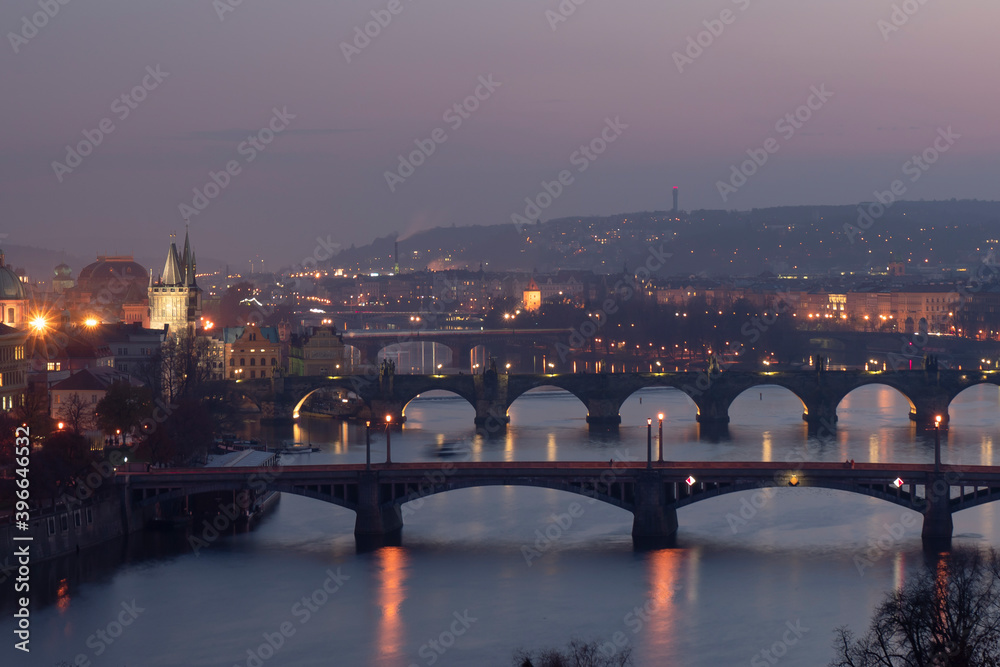 view of the Vltava river and the bridges on it between the bridges and the Charles Bridge and the surrounding architecture and light from the street lights in the center of Prague after sunset view of the Vltava river and the bridges on it between the bridges and the Charles Bridge and the surrounding architecture and light from the street lights in the center of Prague after sunset