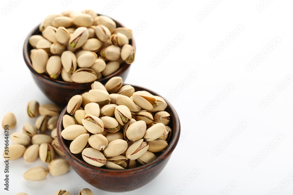 Tasty pistachios in bowls on white background Tasty pistachios in bowls on white background