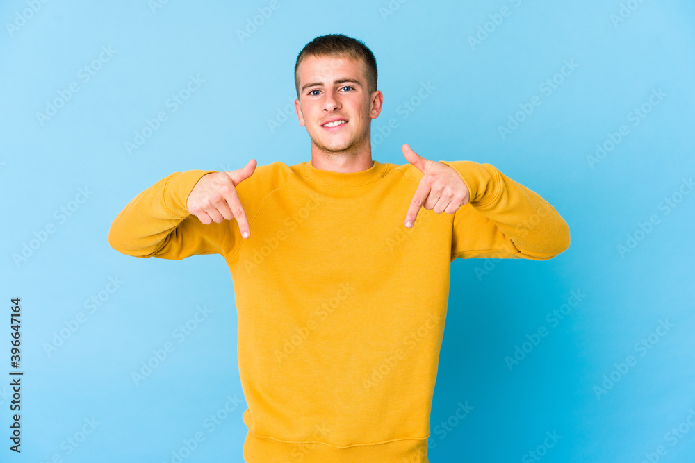 Young caucasian handsome man points down with fingers, positive feeling. Young caucasian handsome man points down with fingers, positive feeling.