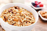 Tasty granola in bowl on brown wooden background