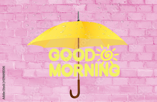 Good morning. The inscription good morning on a pink brick background. Yellow umbrella.