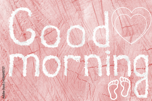 Good morning. The inscription good morning on a pink wooden background. Heart, footprints.