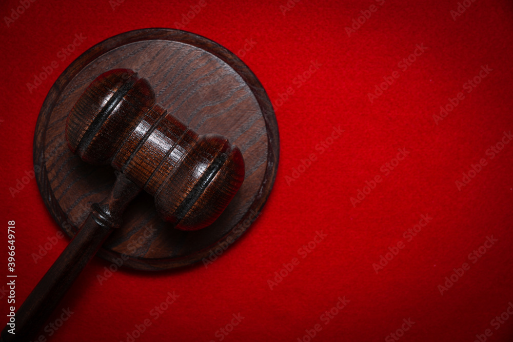 Wooden judge's gavel on a red background. The concept of issuing decisions, verdicts. Accusing and punishing criminals.
