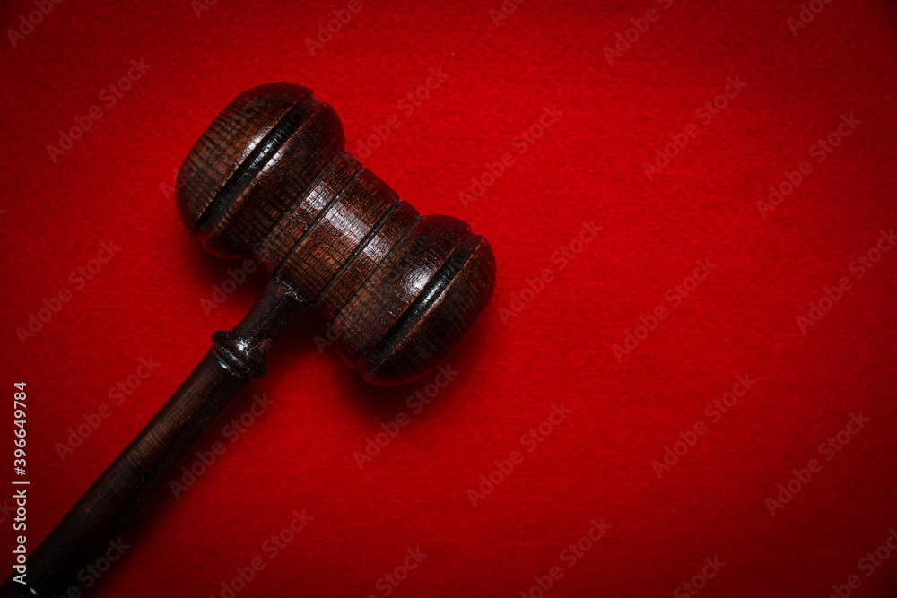 Wooden judge's gavel on a red background. The concept of issuing decisions, verdicts. Accusing and punishing criminals.