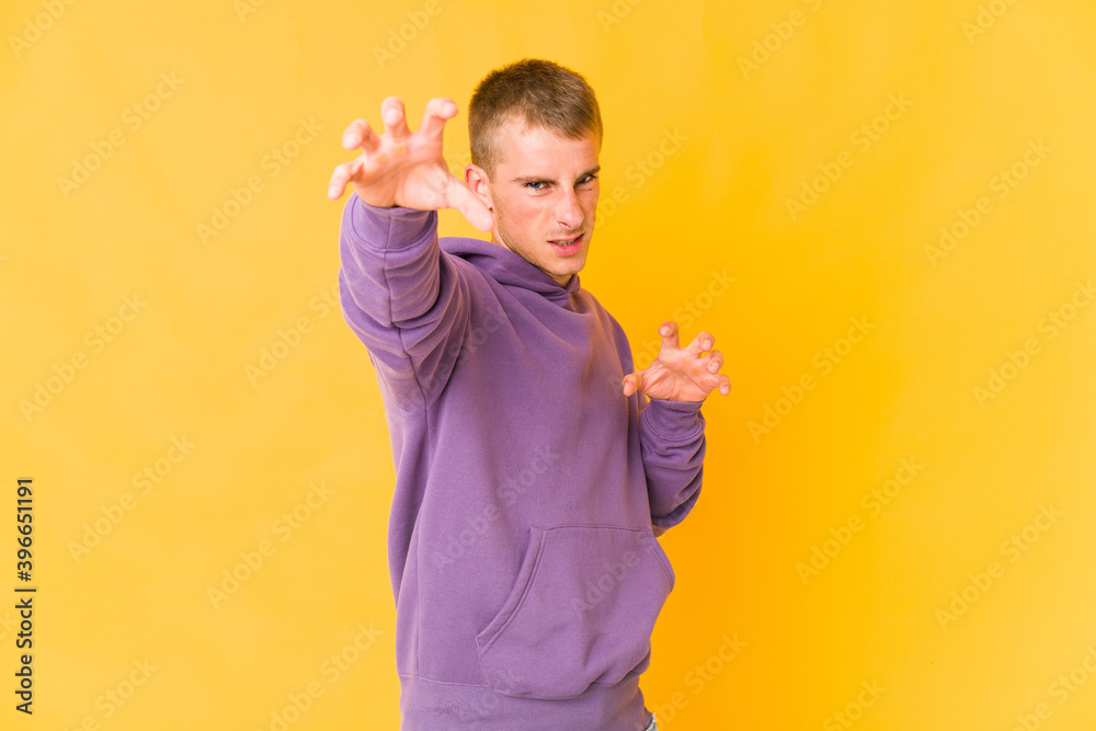 Young caucasian handsome man showing claws imitating a cat, aggressive gesture. Young caucasian handsome man showing claws imitating a cat, aggressive gesture.