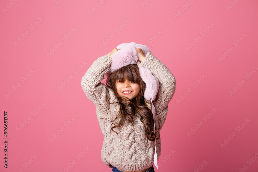 little brunette girl with long hair in winter clothes on a pink background in the Studio. knitwear for children, space for text little brunette girl with long hair in winter clothes on a pink background in the Studio. knitwear for children, space for text
