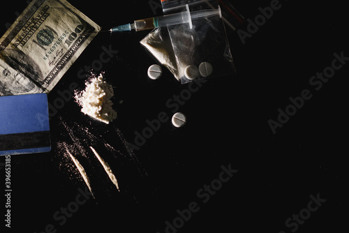 Hard drugs and alcohol on black table. Close up