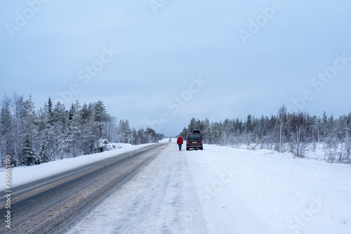 The car is parked on the side of a winter road. Arctic snow straight winter road