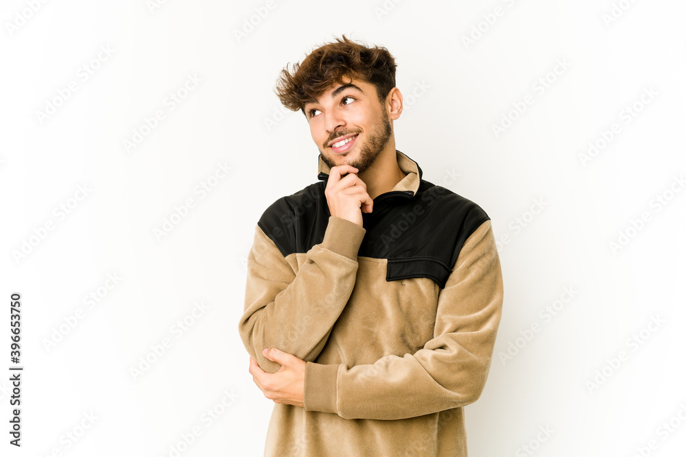 Young arab man on white background relaxed thinking about something looking at a copy space. Young arab man on white background relaxed thinking about something looking at a copy space.