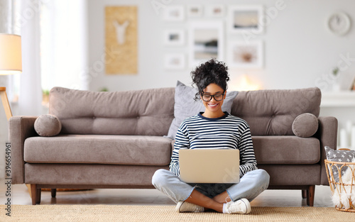 Joyful relaxed ethnic woman using laptop with interest at home.