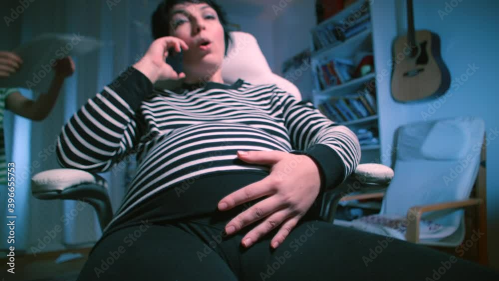 A pregnant woman feels contractions, calls the doctor on the phone. The beginning of labor at home in a chair. A pregnant woman feels contractions, calls the doctor on the phone. The beginning of labor at home in a chair.