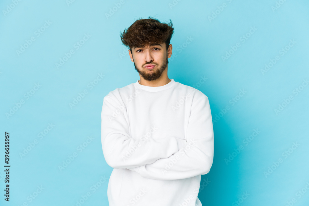 Young arab man on blue background blows cheeks, has tired expression. Facial expression concept. Young arab man on blue background blows cheeks, has tired expression. Facial expression concept.