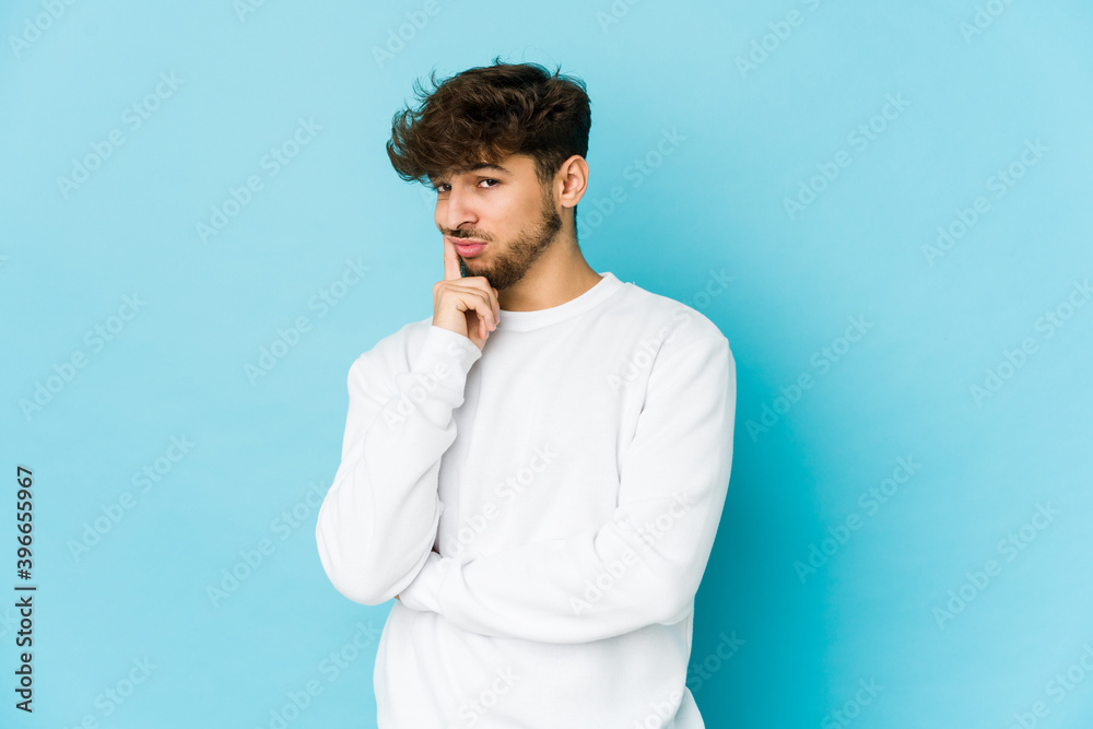 Young arab man on blue background unhappy looking in camera with sarcastic expression. Young arab man on blue background unhappy looking in camera with sarcastic expression.