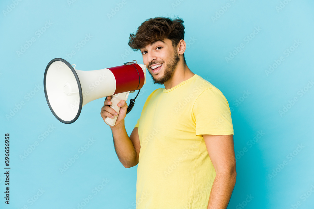 Young arab man holding a megaphone looks aside smiling, cheerful and pleasant. Young arab man holding a megaphone looks aside smiling, cheerful and pleasant.