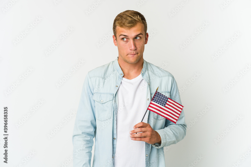 Young caucasian man holding a american flag isolated on white background Young caucasian man holding a american flag isolated on white background