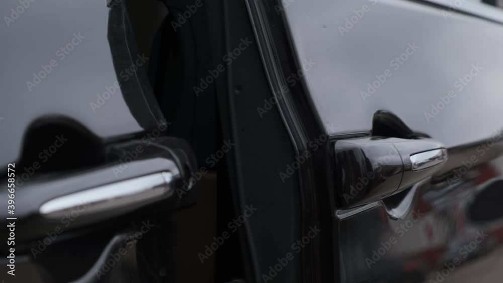 man in black jacket opens door of black minivan with his hand, press button and door slides to the side. man in black jacket opens door of black minivan with his hand, press button and door slides to the side.