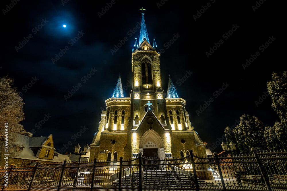  Lutheran church in the Old Town Lutsk, on the background of gloomy winter sky at night. One of the main tourist destinations in the city.  Wide angle view
