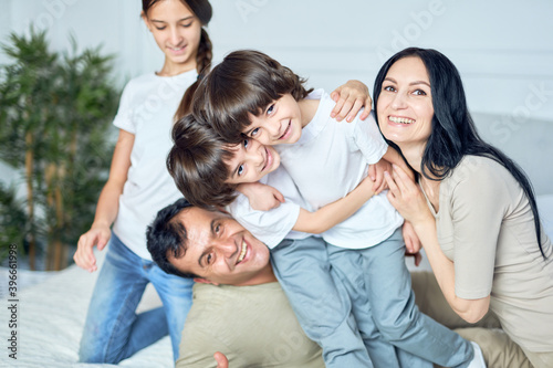 Home is where the family is. Close up portrait of happy latin family, parents and children smiling at camera while gaving fun together at home