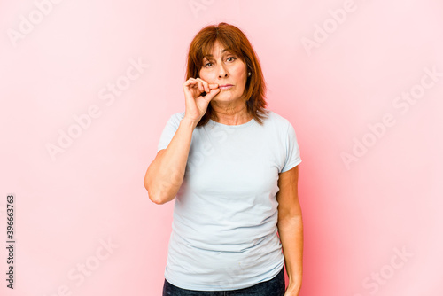 Senior caucasian woman isolated with fingers on lips keeping a secret.