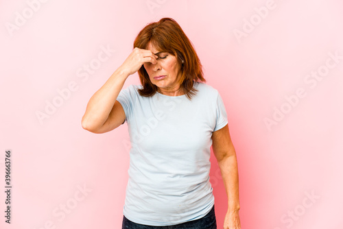 Senior caucasian woman isolated having a head ache, touching front of the face.