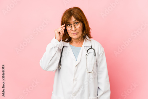 Middle age caucasian doctor woman isolated pointing temple with finger  thinking  focused on a task.