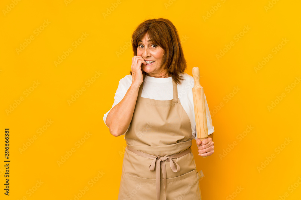 Middle age caucasian cook woman holding a roller isolated biting fingernails, nervous and very anxious. Middle age caucasian cook woman holding a roller isolated biting fingernails, nervous and very anxious.