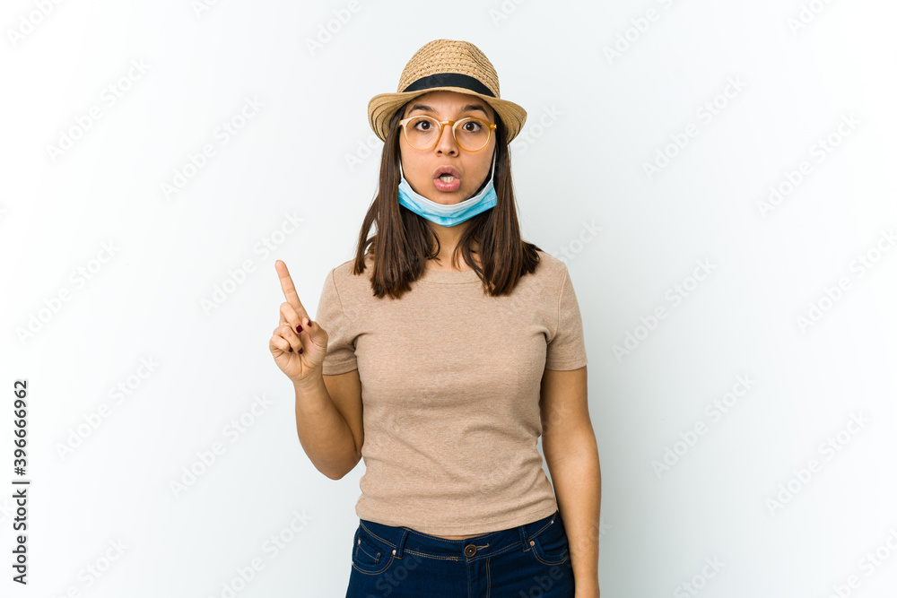 Young latin woman wearing hat and mask to protect from covid isolated on white background having some great idea, concept of creativity. Young latin woman wearing hat and mask to protect from covid isolated on white background having some great idea, concept of creativity.