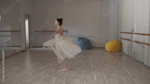 Charming ballerina in the dance hall in front of the mirror in a beautiful dress doing pirouettes photo