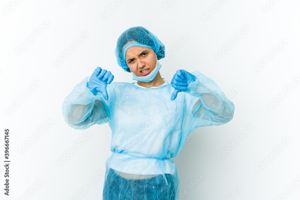 Young surgeon latin woman isolated on white background showing thumb down and expressing dislike. Young surgeon latin woman isolated on white background showing thumb down and expressing dislike.