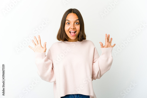 Young mixed race woman receiving a pleasant surprise, excited and raising hands. © Asier