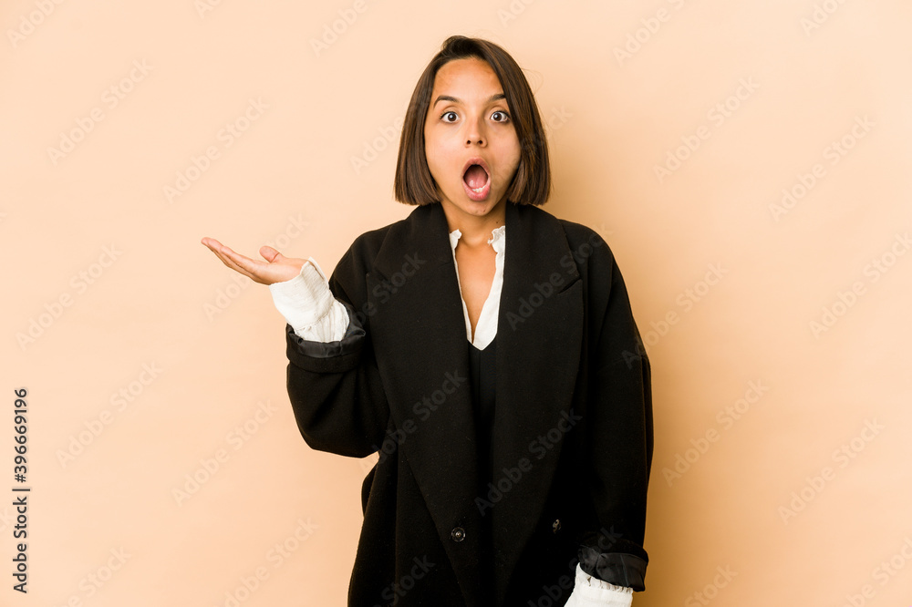 Young hispanic woman isolated impressed holding copy space on palm. Young hispanic woman isolated impressed holding copy space on palm.